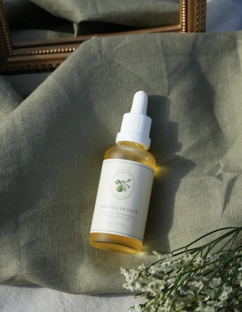 Amber glass dropper bottle of Essenza di Luce skincare oil on olive-green fabric
