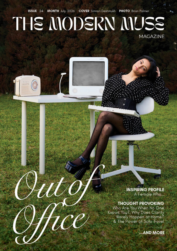 Magazine cover showing a woman in a black polka-dot dress sitting at a white desk outdoors on a grassy field with a vintage computer and radio, bold typography above.