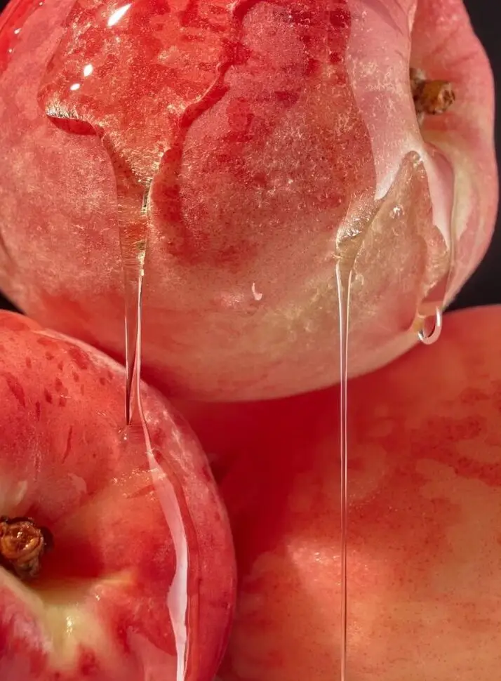 Close-up of ripe peaches with juice dripping from their pink-red skins.